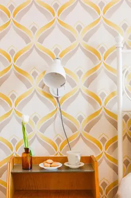 a lamp on a table next to a wall with yellow and white wallpaper at Lovely apt in Rome! in Rome