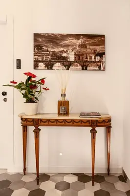 a table with a plant and a picture on the wall at Flora Guest House in Rome