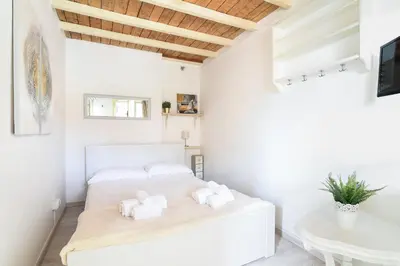 a white bedroom with two beds and a table at Navona studio with terrace Backpackers in Rome