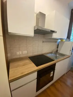 a small kitchen with white cabinets and a stove at San Lorenzo vivace e giovanile in Rome