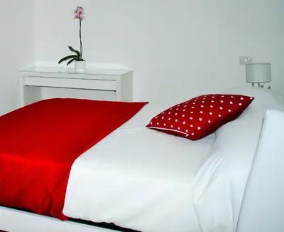a white bed with a red blanket and red pillows at Have A Nice Holiday - Luxury Rooms in Rome