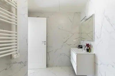 a white bathroom with a sink and a mirror at iFlat Modern Sunlit Studio Apt by the Colosseum in Rome