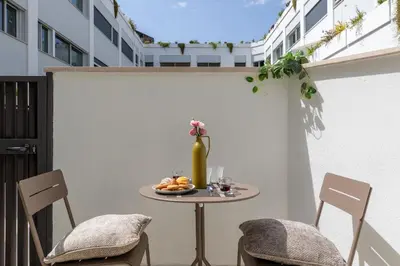 a small table on a balcony with chairs and a vase at iFlat Modern Sunlit Studio Apt by the Colosseum in Rome