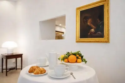 a table with cups and croissants and oranges on it at Modern Flat Historic 1200s Palace Steps from Navona in Rome