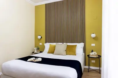 a bedroom with a large white bed with yellow walls at Rome Bliss GuestHouse in Rome