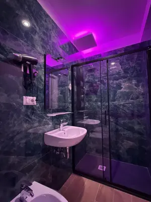 a bathroom with a sink and a toilet with a purple light at Dormire in Trastevere in Rome