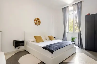 a white bedroom with a bed and a window at Vatican Area Stylish 2BR Fast WiFi & AC in Rome