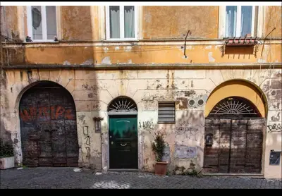 an old building with two gates and a green door at Home trastevere in Rome