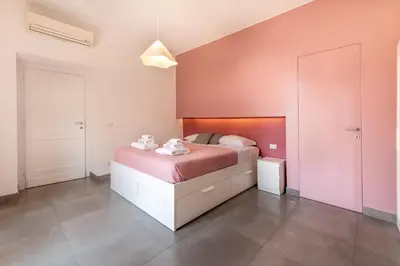 a bedroom with a bed with pink walls at Angelina Domus Saint Peter's in Rome