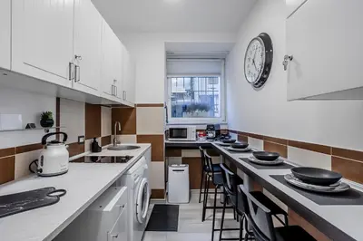 a kitchen with white cabinets and a clock on the wall at Vatican Sweet Dreams Apartment in Rome