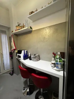 a kitchen with a white counter with red chairs at La casa di Gió in Rome