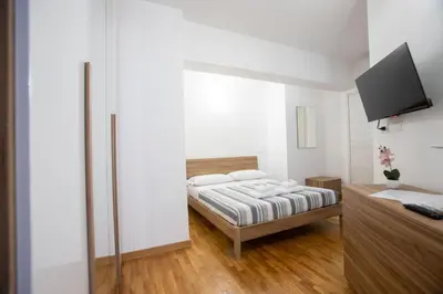 a bedroom with a bed with white walls and wooden floors at VI Domus - Vatican Museum Guest House - Roma in Rome