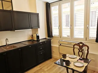 a kitchen with black cabinets and a table and a sink at Casa D'Agata in Rome