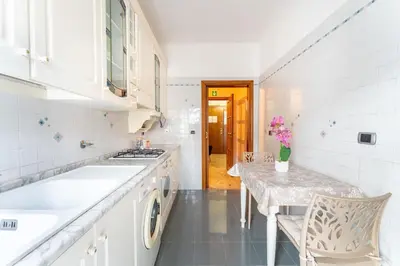 a white kitchen with a table and a sink at 7th Floor Terrace Stay - San Giovanni & Colosseum in Rome
