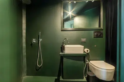 a green bathroom with a toilet and a sink at GuestHost - San Pietro Studio Apartment Roma in Rome