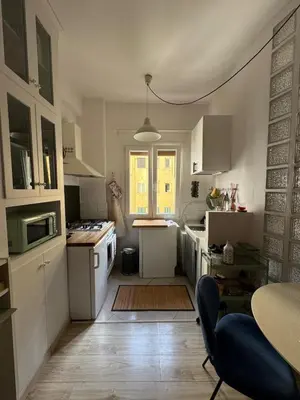 a small kitchen with white cabinets and a table at Appartamento Corso Trieste in Rome