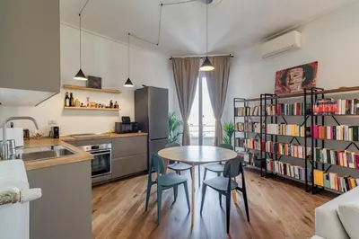 a kitchen with a table and chairs and a book shelf at AureaLiving - Satrico Cozy Apartment fast WIFI and Air Conditioning in Rome