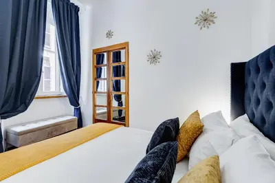 a bedroom with a bed and a window with blue curtains at New Spanish Square - RomeDreamHome in Rome