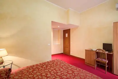 a hotel room with a bed and a desk with a television at Monti Guest House - Affittacamere in Rome