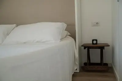 a bed with white sheets and a table with a clock on it at Luxury Apartment - Vatican Area - Key Collection in Rome