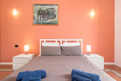 a bedroom with an orange wall with a bed and two lamps at Vista Laterana in Rome