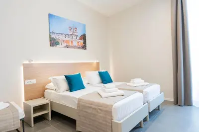 two beds in a white room with blue pillows at imperium suite trevi in Rome