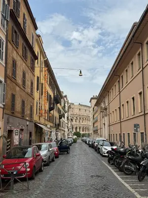 a street with cars parked on a cobblestone street at NOI Luxury rooms Colosseum in Rome