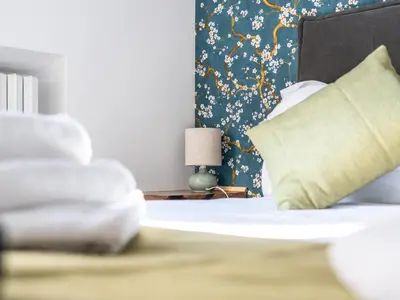 a bedroom with a bed with a blue and gold wallpaper at NOI Luxury rooms Colosseum in Rome