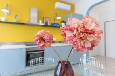 a vase with pink flowers on a table in a kitchen at Domus Veneranda in Rome