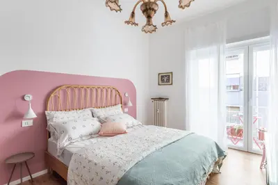 a pink and white bedroom with a bed and a chandelier at Domus Veneranda in Rome