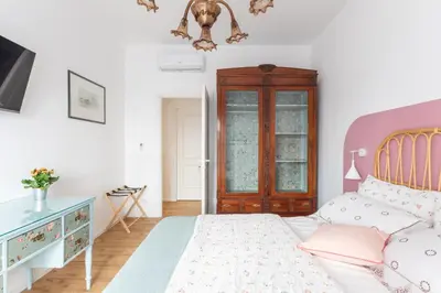 a white bedroom with a bed and a dresser at Domus Veneranda in Rome