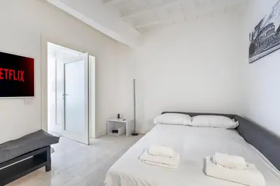 a white bedroom with a large bed with white sheets at Maison Parlamento - Roma centro in Rome