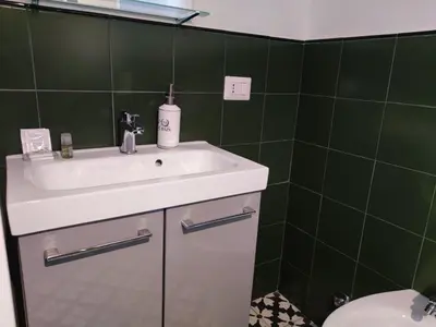 a bathroom with a sink and a green tiled wall at Monti loft al Colosseo in Rome