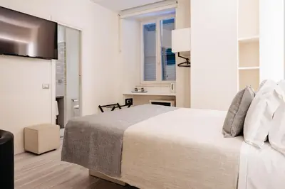a white bedroom with a bed and a kitchen at Room 230 Roma Luxury Suites in Rome