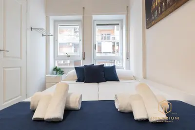 a large white bed in a room with two windows at Imperium Garbatella Guesthouse - 2 bedrooms with private bathroom, Terrace, 800mt to metro in Rome