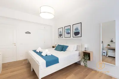 a white bedroom with a large white bed with blue accents at Imperium Garbatella Guesthouse - 2 bedrooms with private bathroom, Terrace, 800mt to metro in Rome