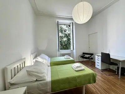 a bedroom with two beds and a desk and a window at La Casabella Rome Center in Rome
