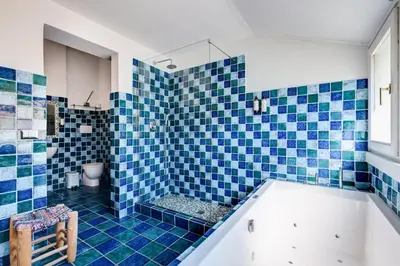 a blue tiled bathroom with a tub and a toilet at Attico incantevole con idromassaggio e terrazzo in Rome