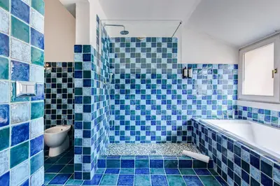 a blue tiled bathroom with a tub and a toilet at Attico incantevole con idromassaggio e terrazzo in Rome