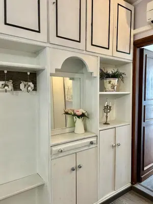 a white hutch with a mirror and flowers in it at La casa di Roby in Rome