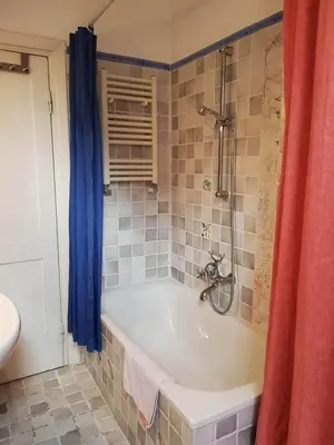 a bath tub in a bathroom with a blue shower curtain at House of Marzia #6000rome in Rome