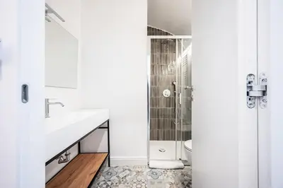 a white bathroom with a sink and a shower at Aeterna RHome - Domus Piramide in Rome