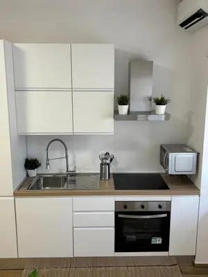 a kitchen with white cabinets and a sink and a microwave at Domus Gregorio VII in Rome