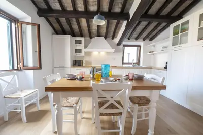 a kitchen with a wooden table and white chairs at Roman Dream in Campo de Fiori in Rome