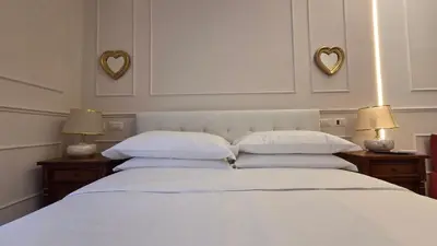 a white bed with two lamps and two hearts on the wall at Luì & Giò Luxury Suite in Rome
