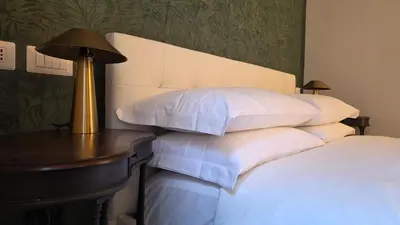 a bed with white pillows and a table with a lamp at Luì & Giò Luxury Suite in Rome