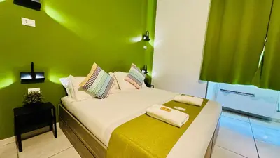 a bedroom with a white bed with a green wall at Star City Guest House in Rome