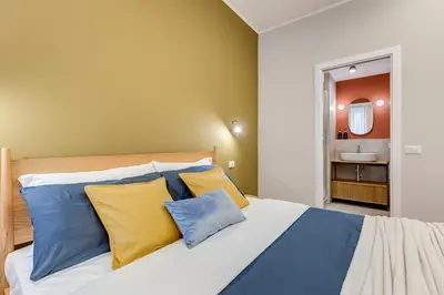 a bedroom with a bed with blue and yellow pillows at BDC - Trevi Premium 3BDR - 3BATH in Rome
