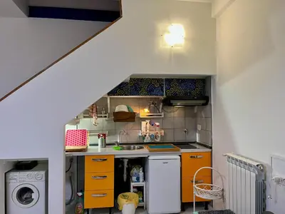 a small kitchen with orange cabinets and a washer and dryer at Trastevere Hideaway in Rome