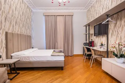 a bedroom with a bed and a table and a desk at Gracchi Vatican View in Rome